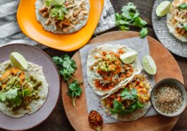 A colorful array of Mexican tacos garnished with lime and cilantro on wooden serving plates