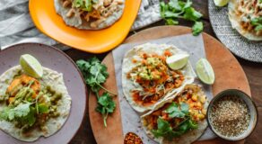 A colorful array of Mexican tacos garnished with lime and cilantro on wooden serving plates