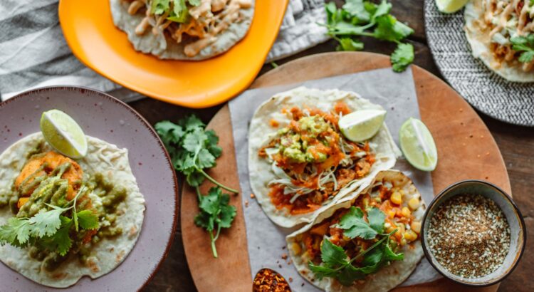 A colorful array of Mexican tacos garnished with lime and cilantro on wooden serving plates