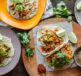 A colorful array of Mexican tacos garnished with lime and cilantro on wooden serving plates