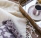 A cozy arrangement of a blanket, decorative pillow, and a cup of coffee on a tray.